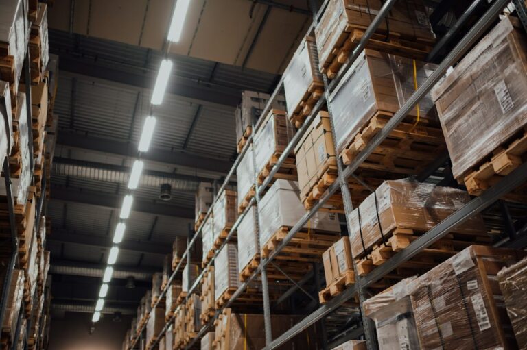 Cajas de cartón almacenadas en estanterías; imagen ilustrativa de logística empresarial, fotografía de CHUTTERSNAP en Unsplash